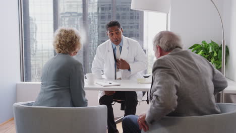 senior couple arriving for hospital consultation with male doctor shaking hands