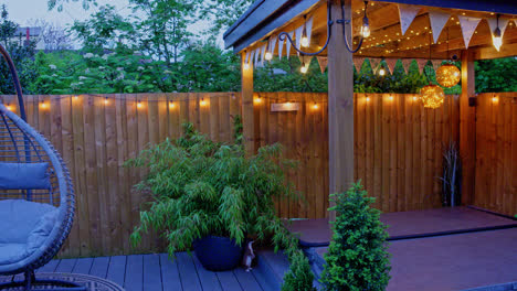 escena del jardín de la tarde de verano que muestra una silla oscilante, una silla de jardín y plantas de bambú en una noche de verano con luces al aire libre