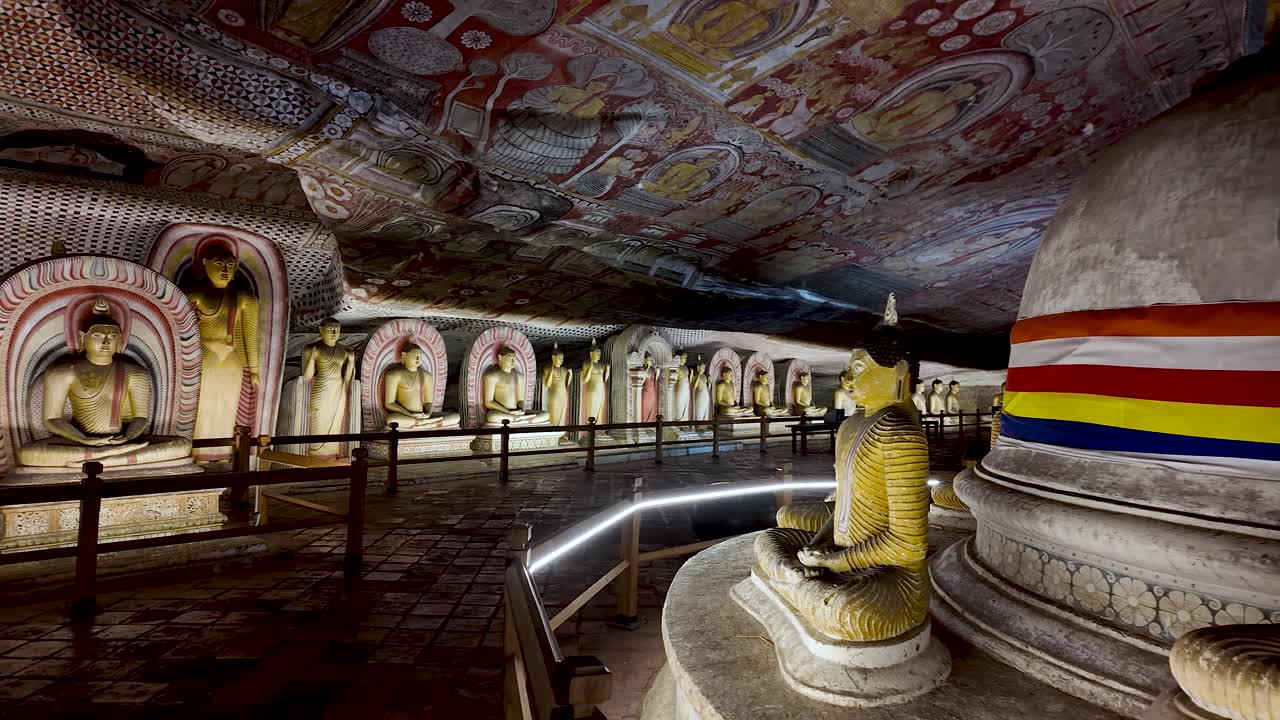 Buddha statues and a stupa inside the Dambulla Cave Temple, featuring a vibrant painted ceiling in Sri Lanka.