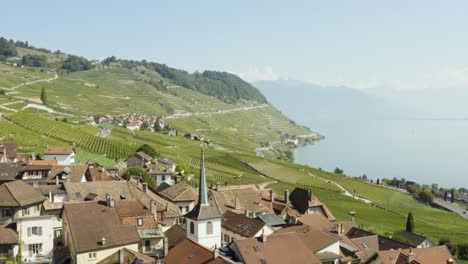 Sobrevolando-El-Típico-Pueblo-Suizo-En-El-Viñedo-De-Lavaux,-Pasando-Cerca-Del-Campanario-De-La-Iglesia---Suiza