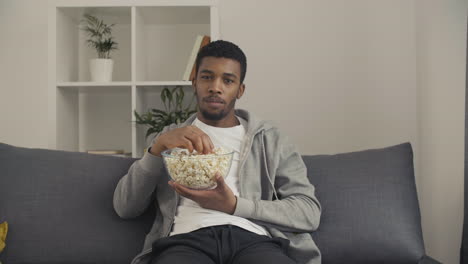 young male looking directly at the camera and showing us a popcorn