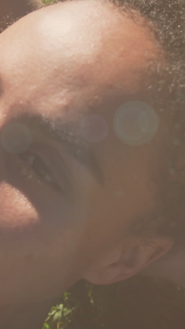 animación de puntos de luz sobre una mujer biracial sonriente tendida en el parque