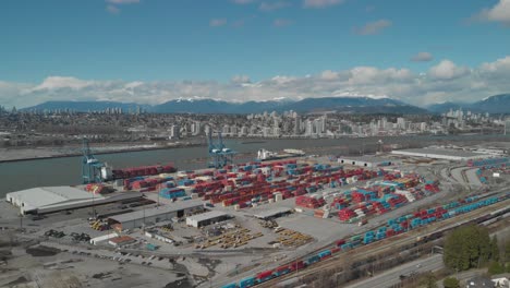 colorful-shipping-containers-stacked-high-and-organized-at-busy-city-port-harbor-dock-on-edge-of-fraser-river-in-Surrey-BC-Canada-Aerial-wide-fixed-angle-and-position