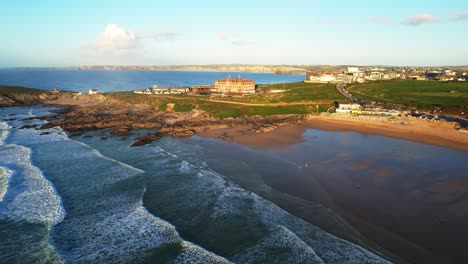 Fistral-Beach-and-Headland-Hotel-in-Cornwall-from-an-Aerial-Drone-Over-the-Surf-During-Warm-Sunlight