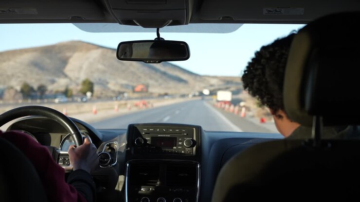 Un autista adolescente che supera un cantiere autostradale mentre impara a guidare - vista dal sedile posteriore del conducente e dell'istruttore al rallentatore