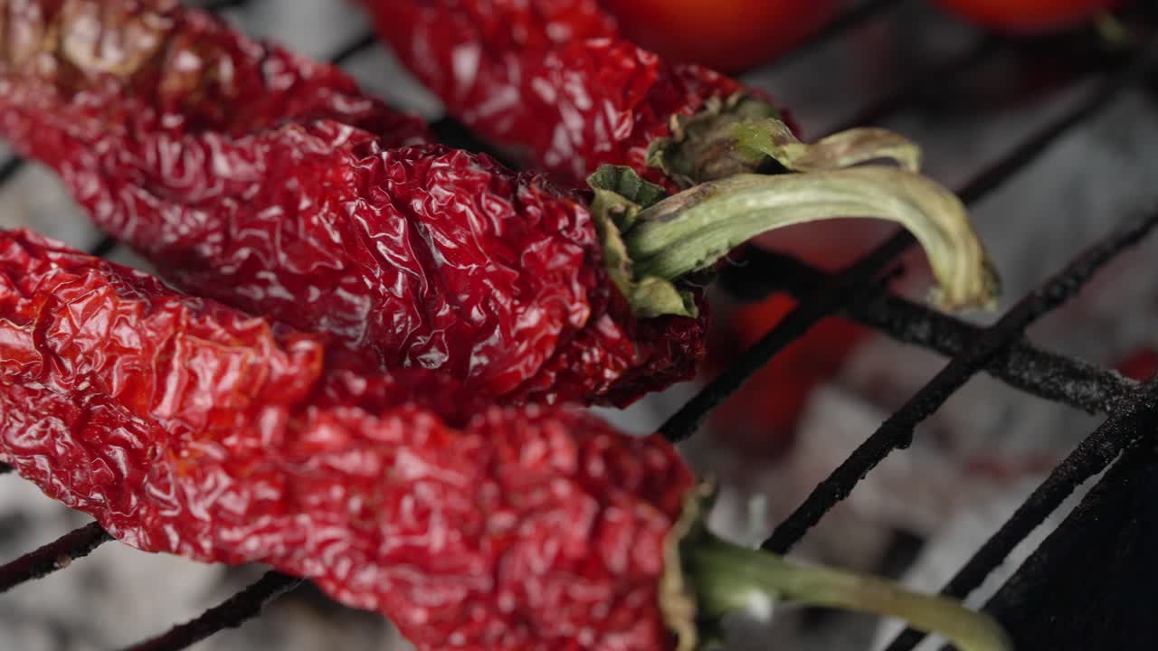 요리사는 건강한 지중해 요리를 준비하기 위해 숯불 그릴에 고추를 넣습니다.