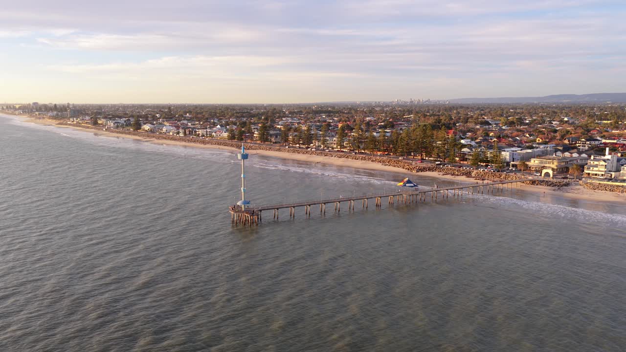 A drone reveal of Brighton Beach, its jetty, and the Adelaide city suburbs - beautiful coastal landscape in South Australia