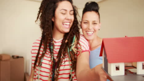 una pareja de lesbianas sonrientes desempaquetando una caja de cartón.