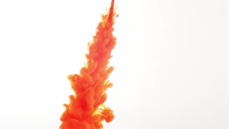 against a plain white background, a plume of orange colored liquid squirts down from above, spreading out into a cloud over time