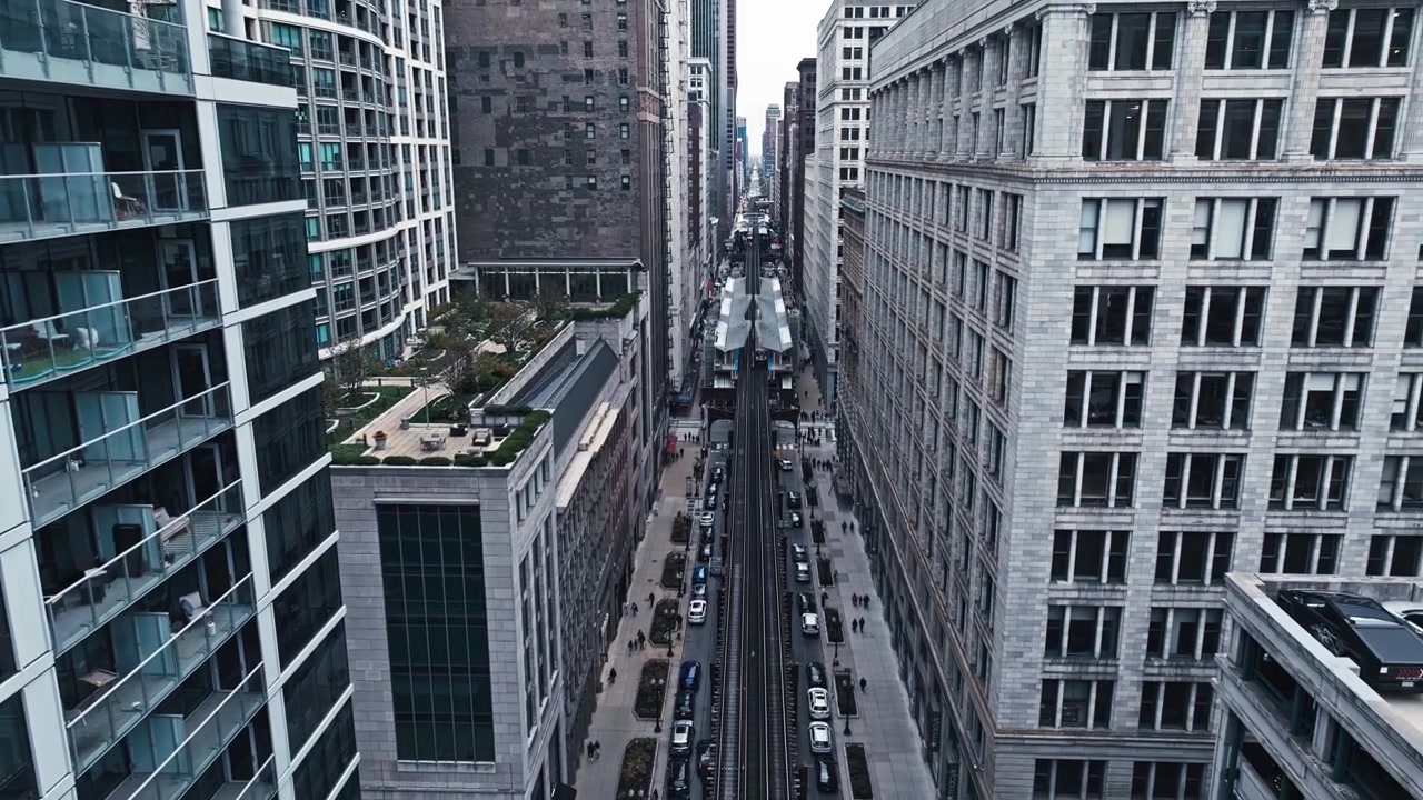 Perspectiva aérea de gran altura de una densa carretera de Chicago con vías de tranvía en medio, rodeada de rascacielos