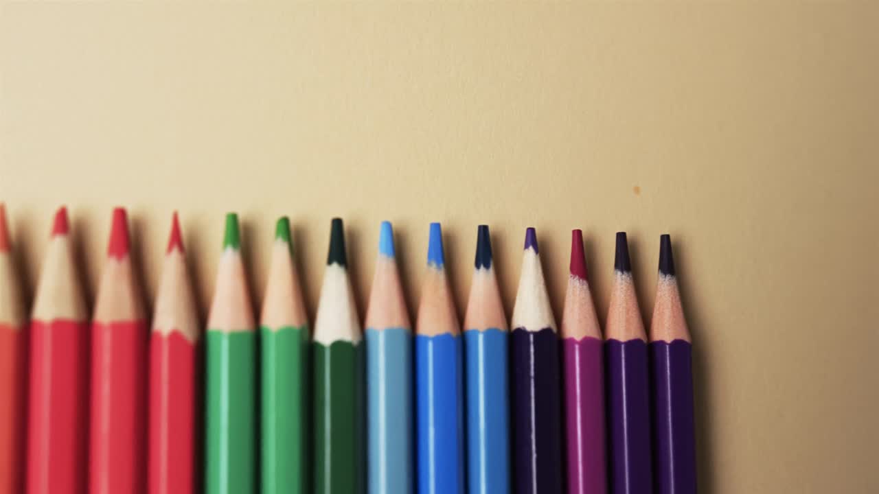 primer plano de lápices de colores dispuestos con espacio de copia sobre fondo beige, en cámara lenta