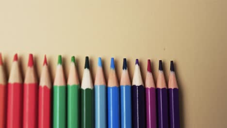 Close-up-of-crayons-arranged-with-copy-space-on-beige-background,-in-slow-motion