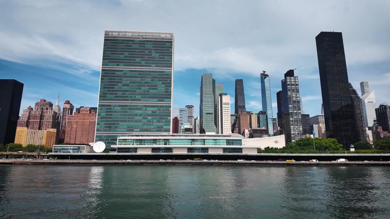 Rampa de velocidade cinematográfica de um barco em movimento passando pela Sede das Nações Unidas, Edifício Chrysler, One Vanderbilt e o horizonte de Midtown East ao longo do East River de Nova York.