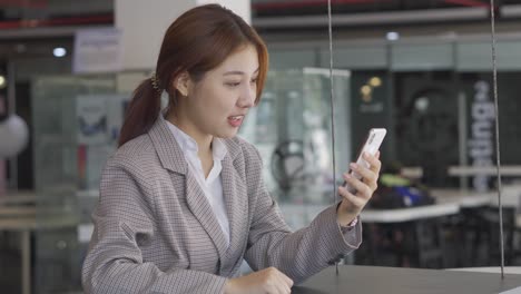 young asian businesswoman holding a smartphone working in accounting and finance in the office with laptop and graph document in computational analysis on a business concept table.