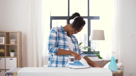 african american woman ironing bed linen at home