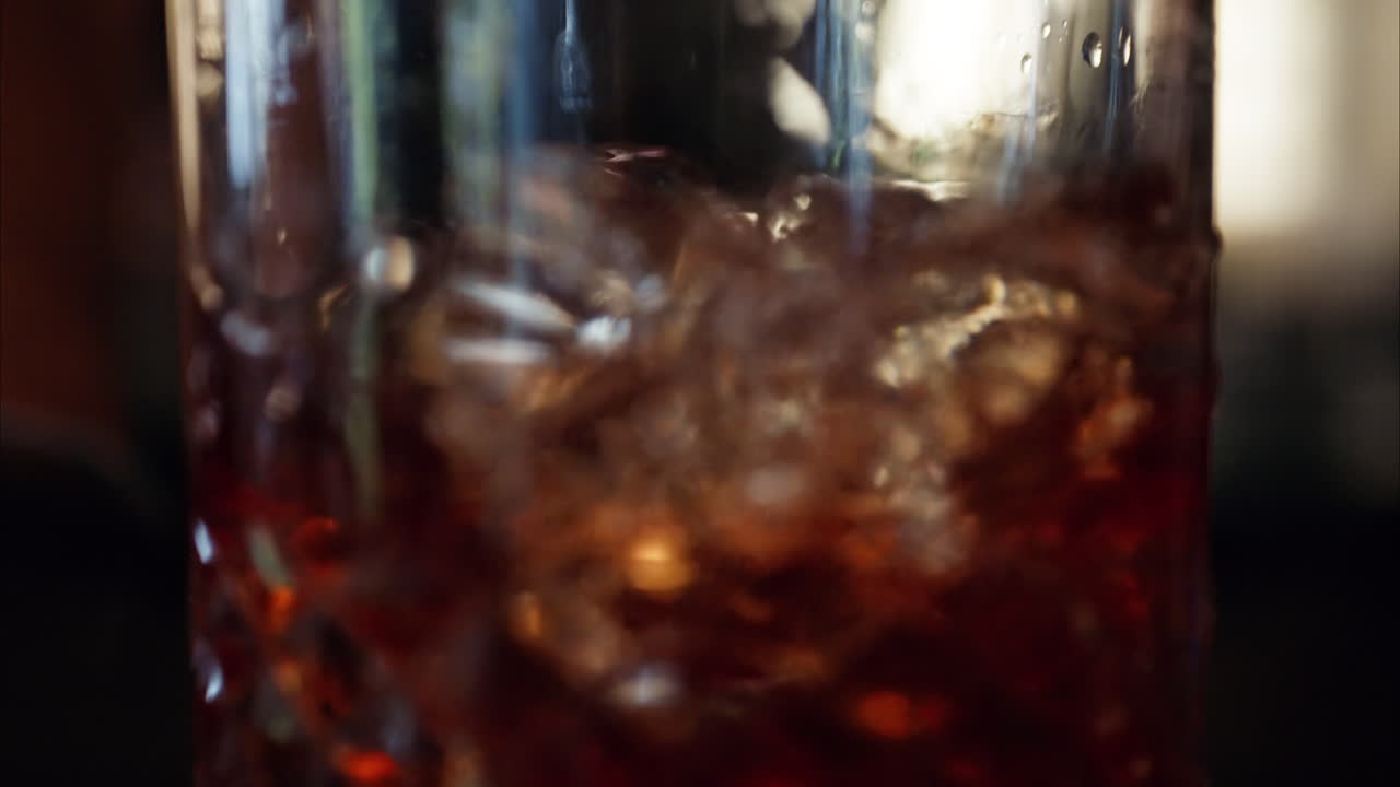Barman che miscela alcolici in un bicchiere con cubetti di ghiaccio