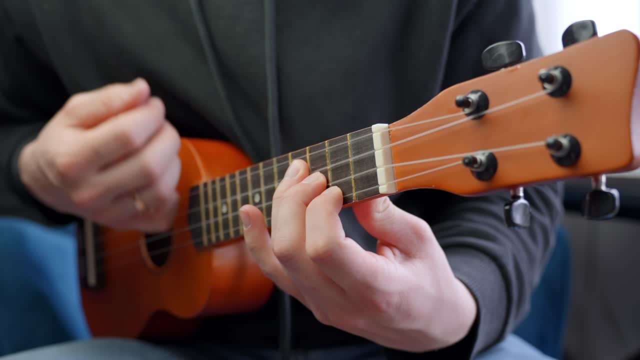 Slow motion view Caucasian male hands play ukulele stringed guitar, music instrument teaching