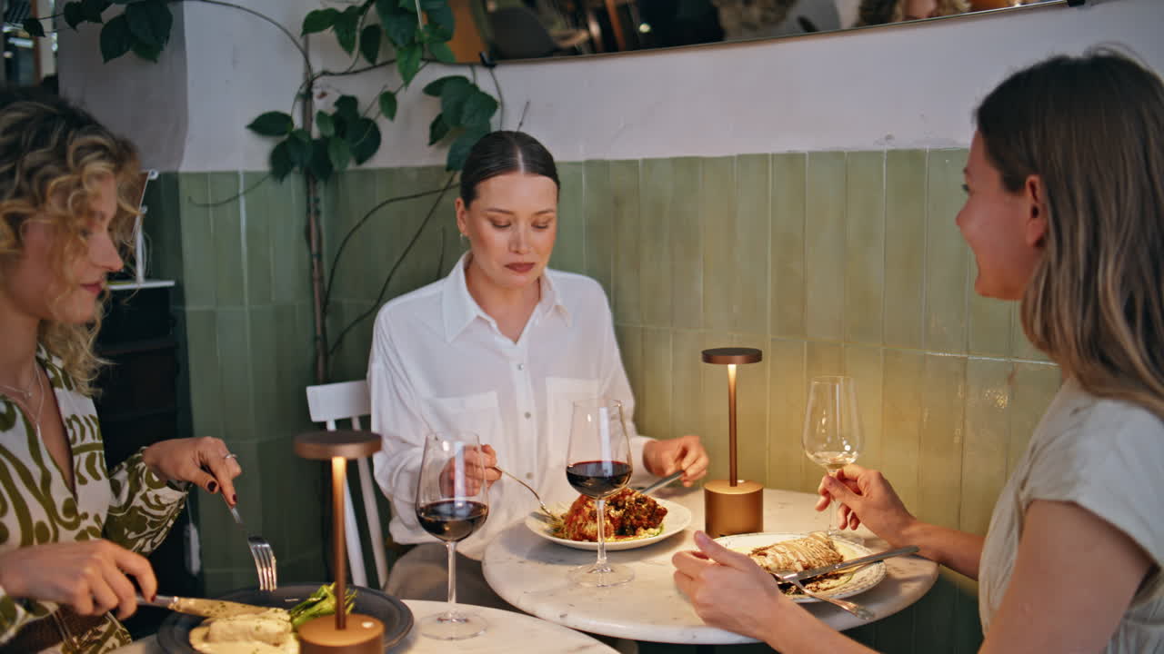 Relaxed three women dining at trendy restaurant engaged in conversation