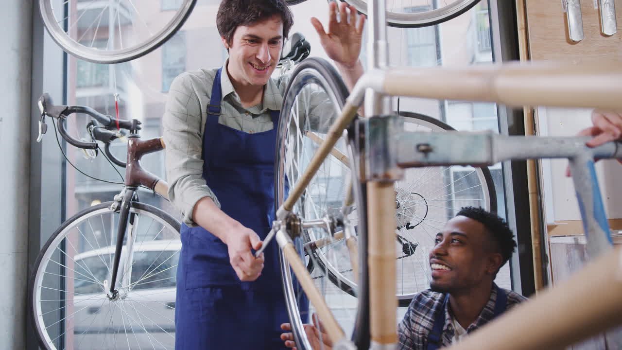 equipo multicultural de aprendices en un taller ensamblando el marco de una bicicleta construida a mano
