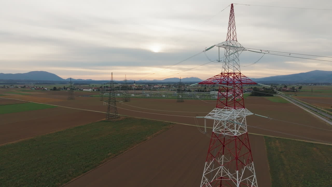 Power lines and electrical towers stand in a rural area as the sun sets showcasing energy