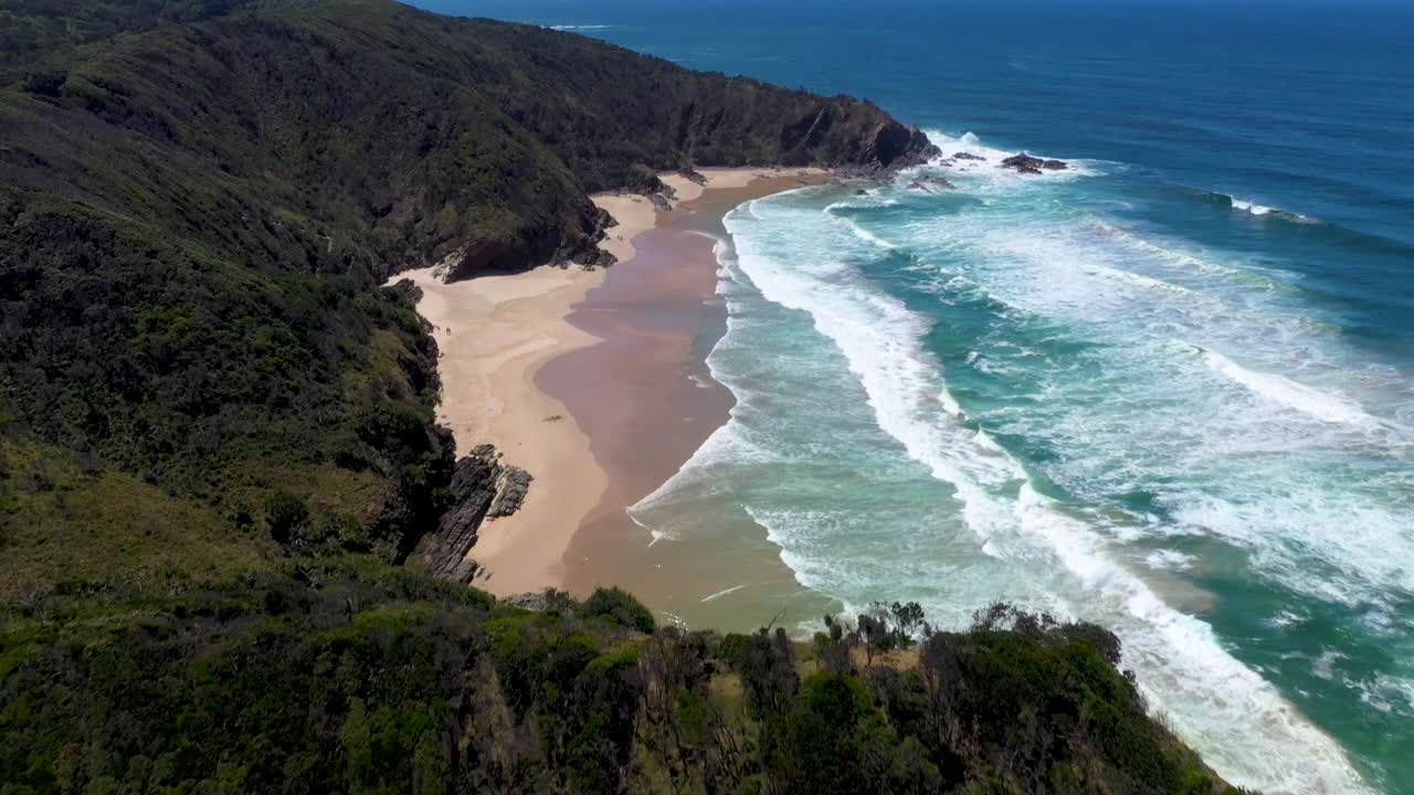 Ripresa cinematica con drone che si inclina verso l'alto su oceano e isola a Wategos Beach, Australia