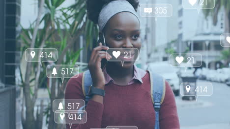 Animation-Von-Social-Media-Symbolen-Mit-Wachsender-Zahl-über-Einer-Afroamerikanischen-Frau,-Die-Ihr-Smartphone-Nutzt