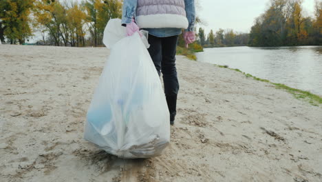 un niño voluntario arrastra una bolsa de basura pesada a lo largo de la playa limpiando los desechos y el activismo sigue a sh