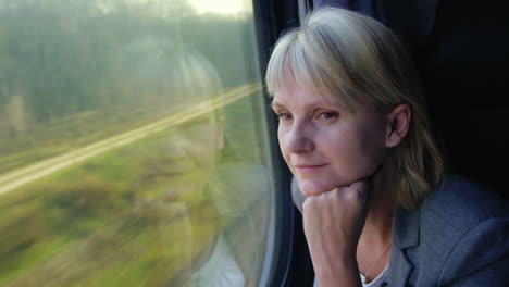 young woman travels by train looks out the window at beautiful scenery dreams slow motoin video