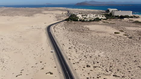 drone dolly en tiro en la carretera, viendo un complejo hotelero en la playa de corralejo, fuerteventura, islas canarias