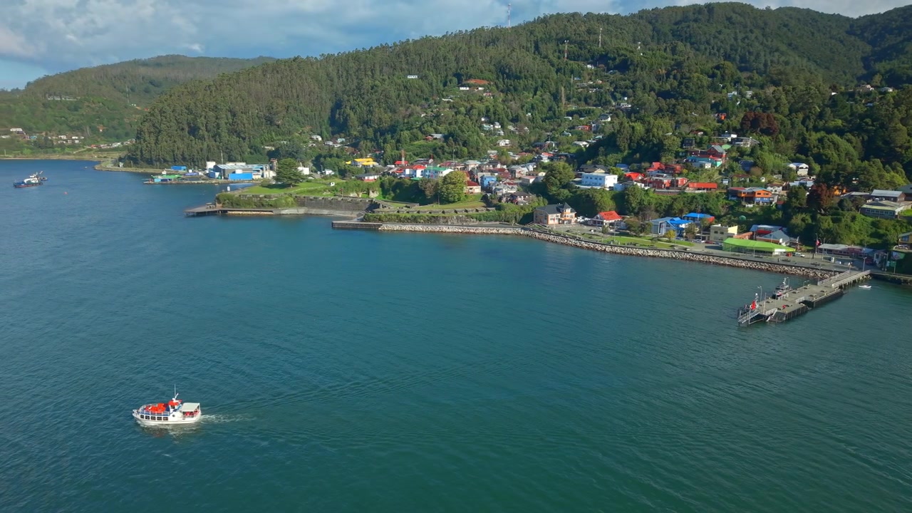 Valdivia, Şili'deki Corral'ın güneşli bir günde, doğal çevrenin ve berrak suların ortasında, kıyılarında bir turist teknesiyle panoramik havadan görünümü