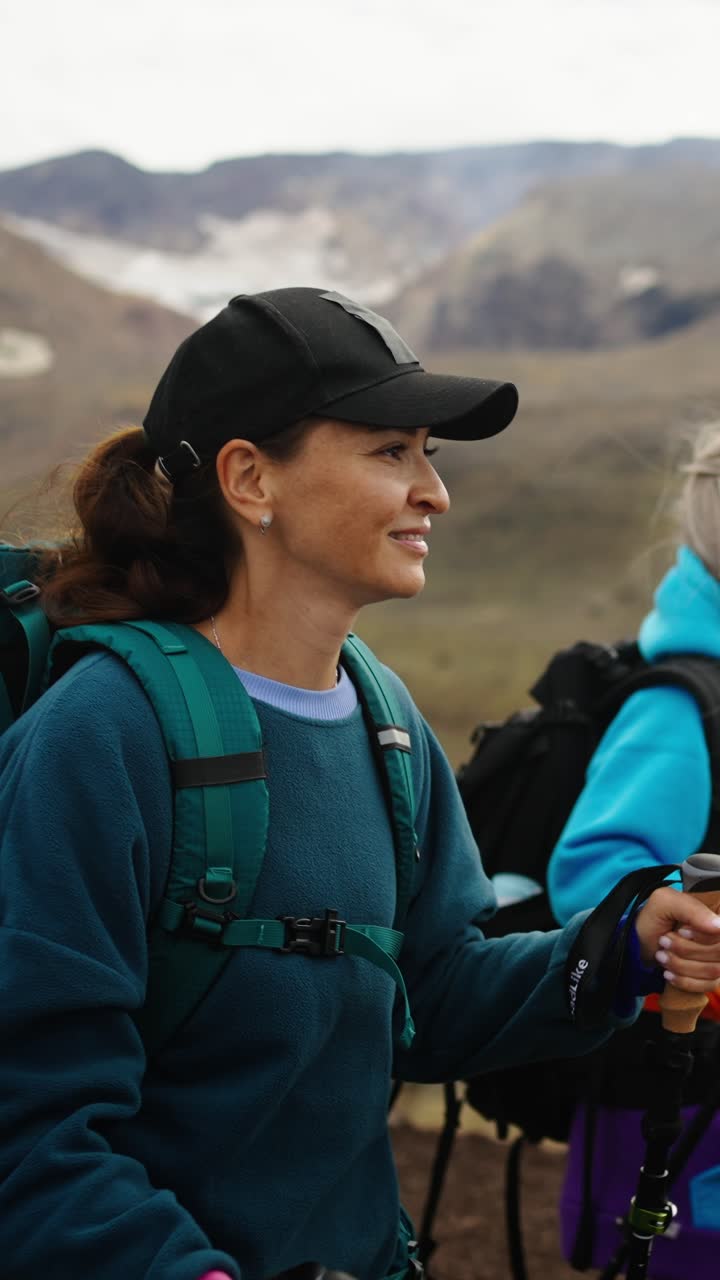 Donna in escursione con zaino e bastoncini in paesaggio montano