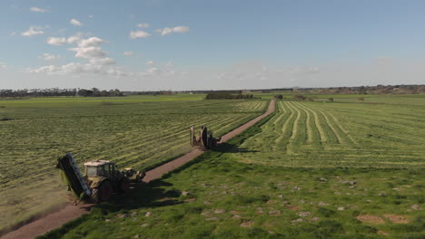 aerial footage following two tractor mowers from the side