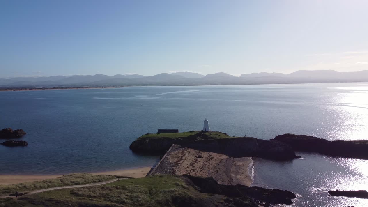 vista aérea de la idílica isla de ynys llanddwyn con la nebulosa cordillera de snowdonia a través del brillante mar de irlanda hacia el faro