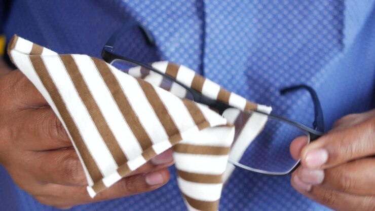 Cleaning eyeglass with tissue close up