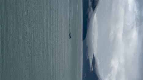 Un-Barco-De-Pesca-Cruza-Un-Fiordo-A-Lo-Largo-De-La-Costa-De-Alaska---Orientación-Vertical