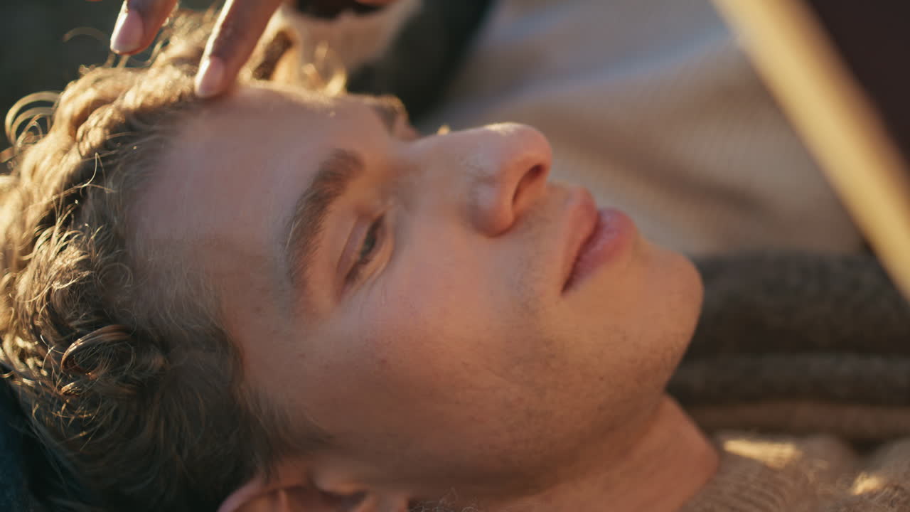 Woman hand stroking man head at warm sunlight closeup. Boyfriend lying knees