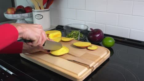 woman cubing freshly cut mango for fresh salsa