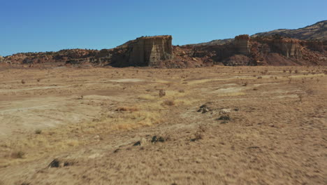 Desert-aerial-passing-over-car-on-dirt-road-to-reveal-rock-formations