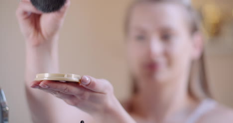 Young-Woman-Using-Brush-And-Powder-While-Doing-Make-Up-2