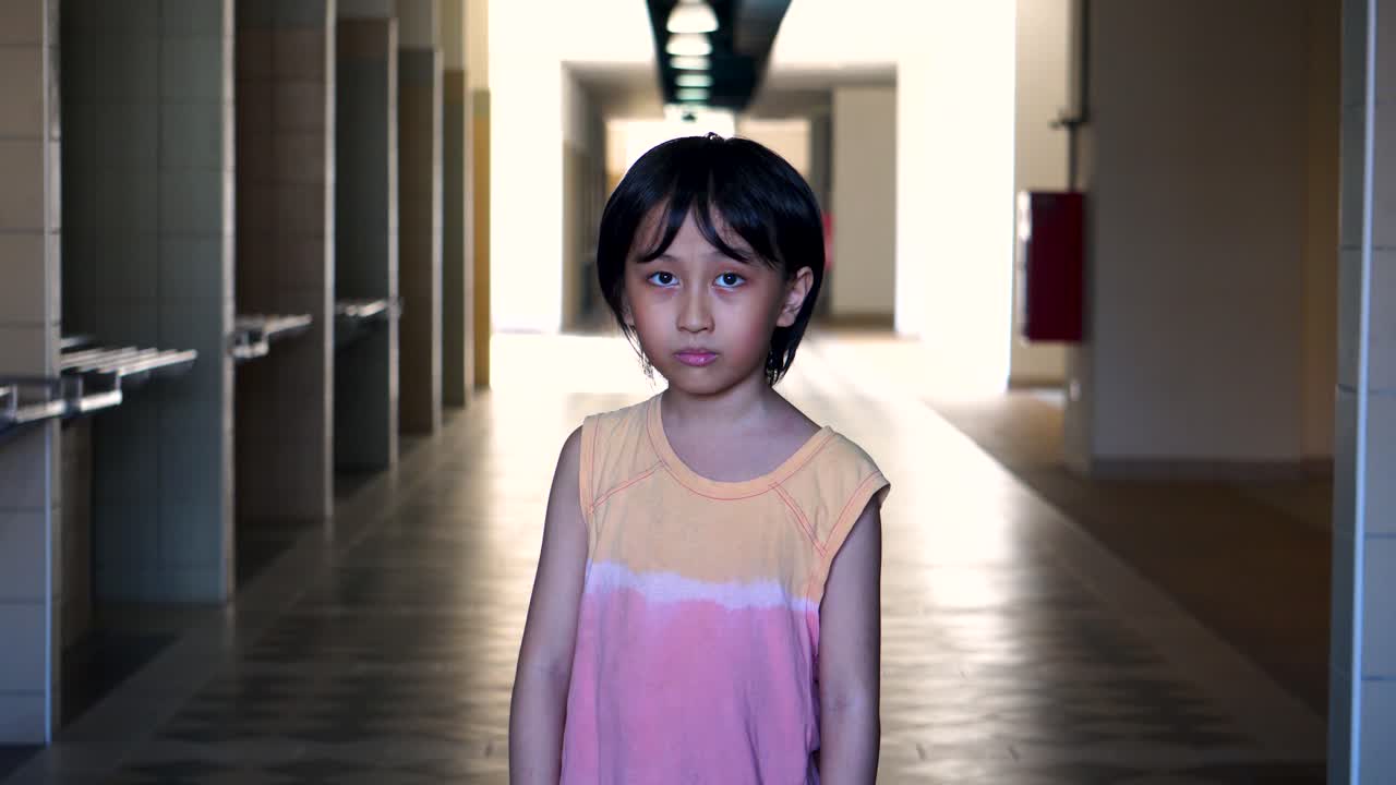 retrato de un joven del sudeste asiático solo asustado mirando a la cámara en un pasillo abandonado del centro comercial con luz y sombra en el fondo