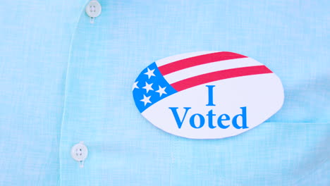 Man-puts-I-Voted-sticker-with-American-Flag-on-the-shirt