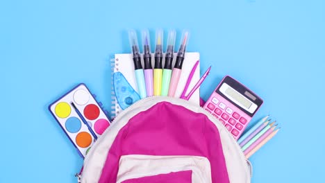 back to school stationery appear from backpack on blue background. stop motion