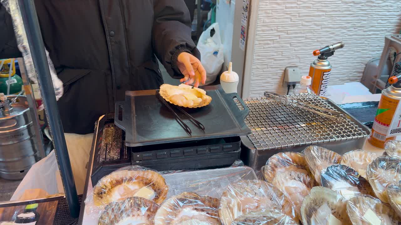 A vendor prepares fresh scallops on a grill at Tsukiji Outer Market in Tokyo
