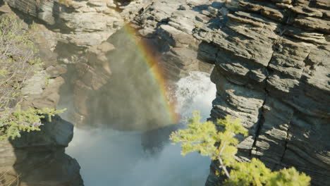 la luz del sol se refracta como un arco iris en la niebla de la cascada - las cataratas athabasca
