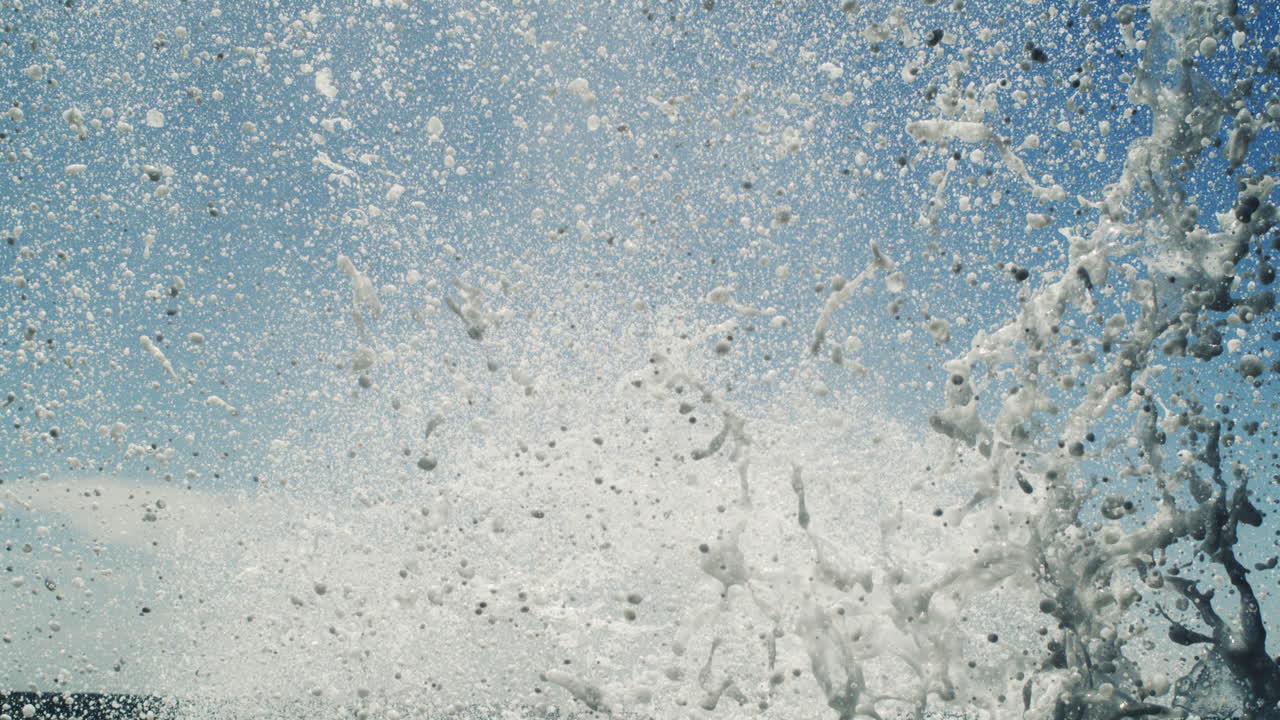 Super slow-motion water column bursts skyward from ocean surface in powerfully lit scene