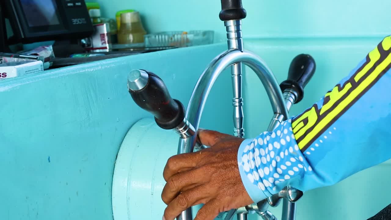 Close-up of hands expertly maneuvering a yacht's steering wheel, showcasing control and focus in a nautical setting.