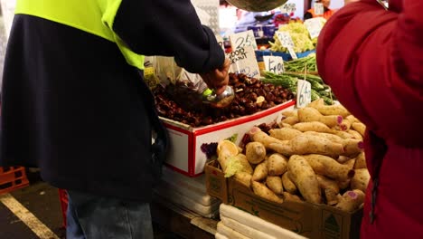 people scooping chestnuts at a market stall