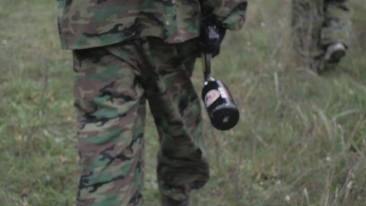 jugador de paintball caminando por el bosque en cámara lenta