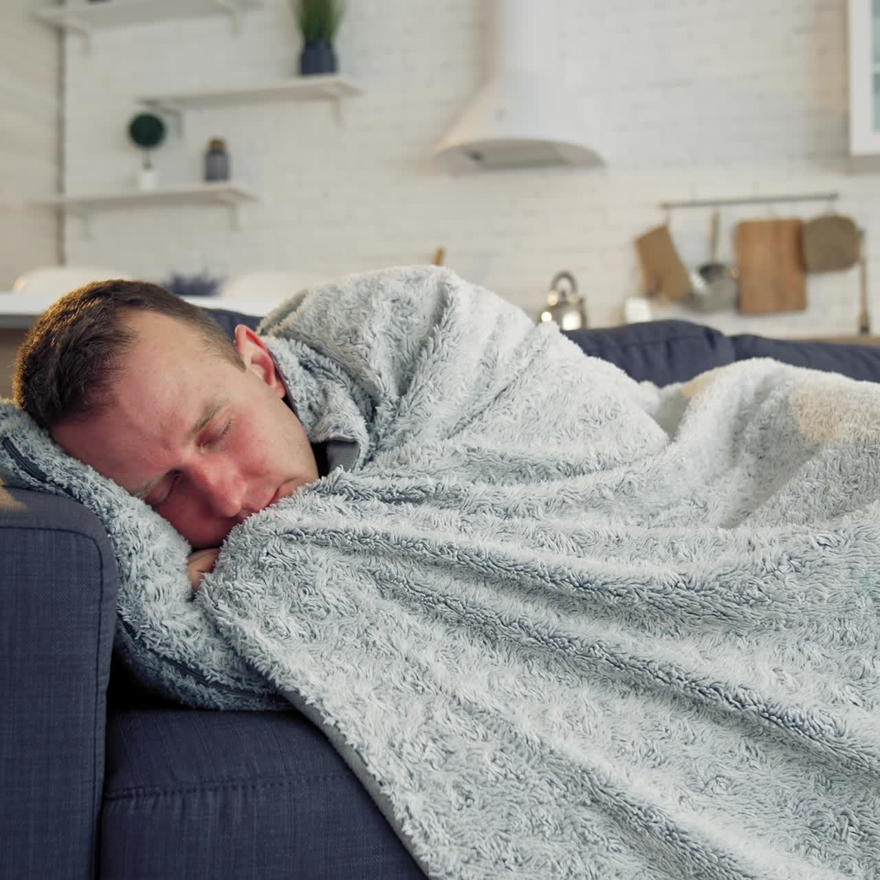 Sick man under warm blanket on comfortable couch at home. Pandemic. Quarantine concept