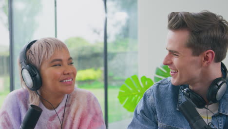 Portrait-Of-Couple-Wearing-Headphones-Vlogging-With-Microphone-On-Live-Stream